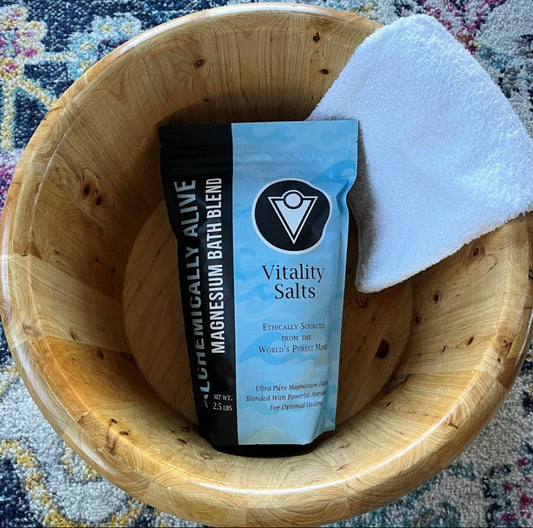 Vitality Salts package in a wooden bowl with a towel on a patterned rug
